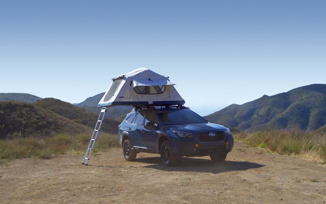 A Subaru Outback Wilderness with a tent on top of the vehicle